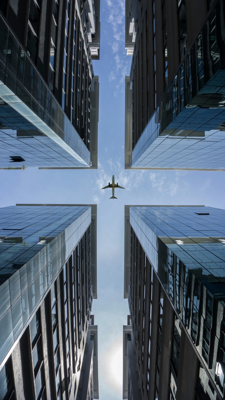 Airplane flying between modern buildings